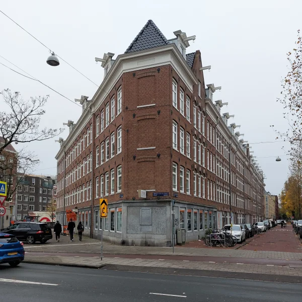 Afbeelding uit: november 2024. De scherpe hoek Hugo de Grootplein (links) - Van Houweningenstraat, met plaquettes in de plint.