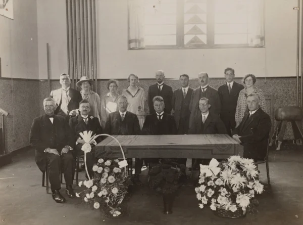 Afbeelding uit: september 1927. Groepsfoto in de gymzaal, gemaakt bij de opening van de school. Zittend vermoedelijk het schoolbestuur, staand het personeel.
Bron afbeelding: SAA, bestand OSIM00002000076.
