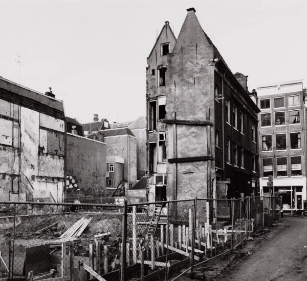 Afbeelding uit: december 1982. Het bouwterrein gezien vanuit de Zanddwarsstraat. Er werd om de monumentale panden op nummer 16 en 19 heen gebouwd.
Bron afbeelding: Stadsarchief.