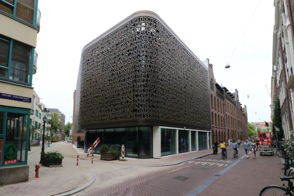 Afbeelding uit: juli 2025. De nieuwbouw op het voorheen onbebouwde terrein. De tekst "Lees maar, er staat niet wat er staat" is een dichtregel van Martinus Nijhoff.