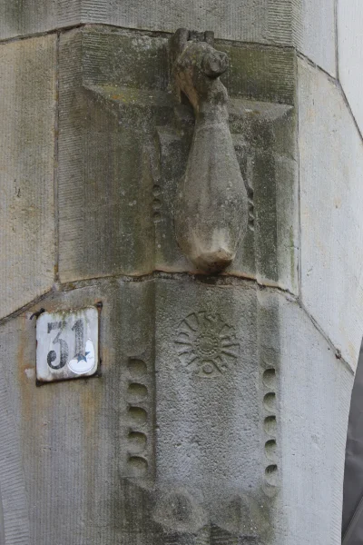 Afbeelding uit: augustus 2025. Detail op de hoek Dam-Rokin: een onderarm met hamer boven de in de vorm van een cirkel geplaatste letters van Industria.