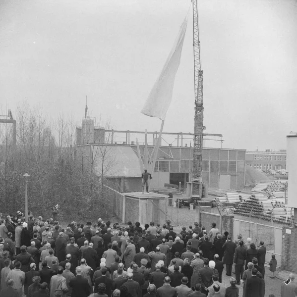 Afbeelding uit: november 1961. Bij het vijftigjarig bestaan van De Waal's Industrie werd bij het vorige gebouw dit beeldhouwwerk geplaatst, gemaakt door Dick Stins. Het toont een arbeider met drie heipalen. In 1970 werd het verplaatst naar Hoogezand.