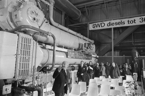 Afbeelding uit: januari 1975. De montagehal werd in 1975 officieel in gebruik gesteld door premier Den Uyl (voorgrond). Op de achtergrond, met ambtsketen, burgemeester Samkalden. Links een TM620.