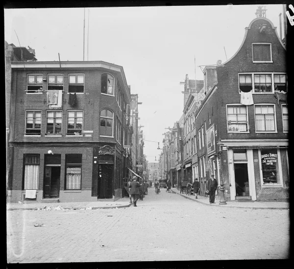 Afbeelding uit: 1930. Rechts de voorganger van het huidige hoekhuis. Op het raam staat "Brood & Banketbakkerij „De Ruiter” Nº 5"