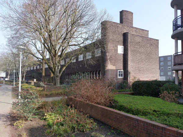 Afbeelding uit: maart 2026. De zijgevels zijn composities van schijven met typische Amsterdamse School-elementen als rondingen en golfjes.