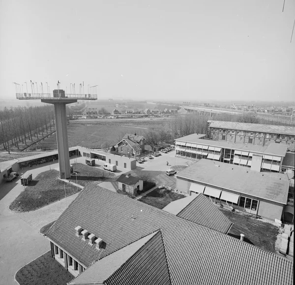 Afbeelding uit: april 1980. Foto gemaakt vanaf een van de antenneplatforms. Geheel onder staat het machinegebouw, in het midden een van de dienstwoningen en rechtsachter het ontijzeringsgebouw. Daartussen nieuwere gebouwen van de rijksluchtvaartdienst.