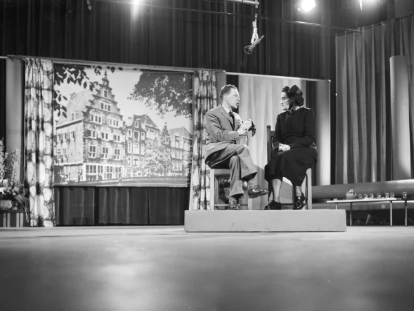 Afbeelding uit: februari 1959. Foto van het eerste televisie-optreden in 1959 van de Amsterdamse majoor Alida Bosshardt (rechts; 1913-2007). Het bracht haar landelijke bekendheid. Op de achtergrond het door haar geleide Goodwillcentrum, pand de Leeuwenburgh aan de OZ Voorburgwal 14.