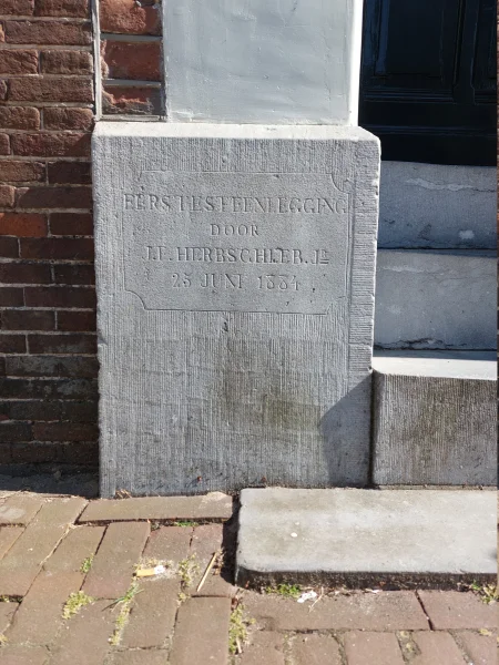 Afbeelding uit: juli 2026. "Eerstesteenlegging / door / J.F. Herbschleb Jʳ / 25 juni 1884"