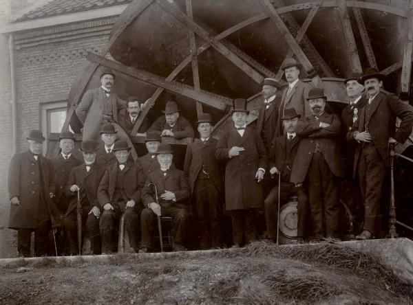 Afbeelding uit: september 1910. Bestuurders van het hoogheemraadschap en andere notabelen bij een proefneming van de vernieuwde schepraderen. Voorste rij, zevende van links: dijkgraaf G. van Wijngaarden. Staand, met hoge hoed en sigaar: penningmeester C. Koker, wethouder en makelaar te Broek in Waterland. Rechts van hem, staand: J. Horn, de directeur van het gemaal.