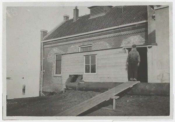 Afbeelding uit: 1916. De machinist van het gemaal staat op de buizen van het in 1916 gebruikte hulpgemaal. Bron: Noord-Hollands Archief / Collectie 559 van foto's van de Provinciale Atlas Noord-Holland, inventarisnummer 119.
