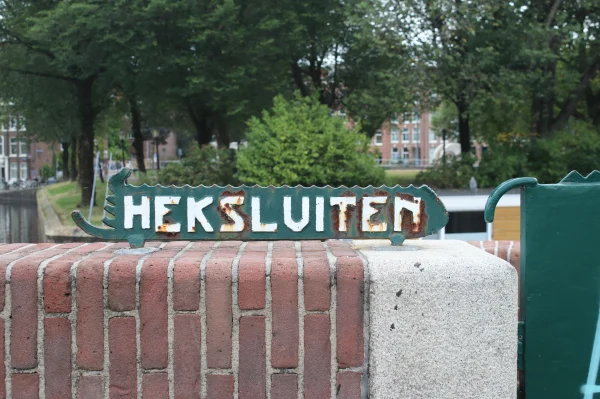 Afbeelding uit: augustus 2026. Bordje bij het hek van de trap naar de basculekelder.