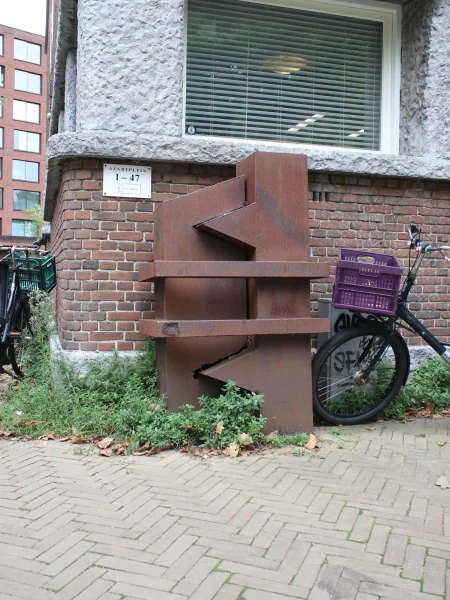 Afbeelding uit: september 2026. Het cortenstalen kunstwerk De Kus van beeldhouwer en bewoner Maarten Loonen (1957-2021) staat naar verluidt al sinds 1983 tegen de zijgevel van het gebouw.