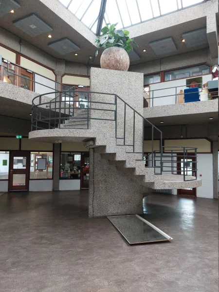 Afbeelding uit: september 2026. Een van de twee betonnen wenteltrappen. De trap staat in een vijfkantige vide.