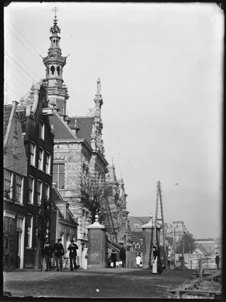 Afbeelding uit: 1891. Het raadhuis in aanbouw. Op de voorgrond het tolhek, waar tol geheven werd tussen de gemeentes Nieuwer-Amstel en Amsterdam. De grens tussen de gemeentes lag een stukje verder naar het noorden, ongeveer bij de Ceintuurbaan.