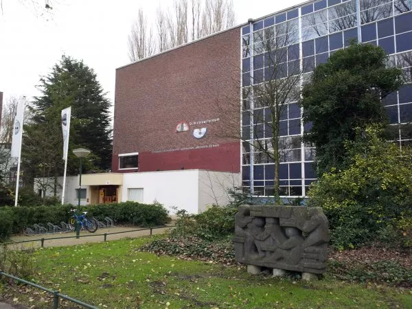 Afbeelding uit: november 2011. De hoofdingang. Het beeld rechts symboliseert de studerende jeugd en werd gemaakt door Frans van der Burgt.