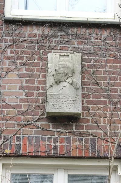 Afbeelding uit: februari 2012. Gevel Bernard Kochstraat. Stenen reliëfportret van D. Linschoten, voorzitter van Rochdale van 1925 tot 1953. Het werd in 1957 onthuld.