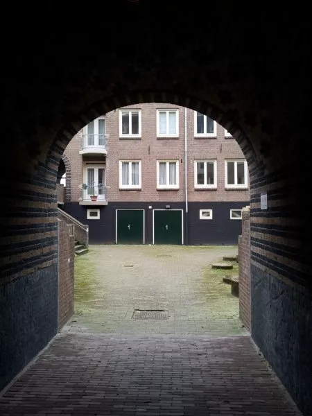 Afbeelding uit: maart 2012. Poortje naar het binnenterrein (Polanenhof) in de gevelwand van het Zaandammerplein. Links zijn de trap en de poort naar de Spaarndammerdijk te zien.