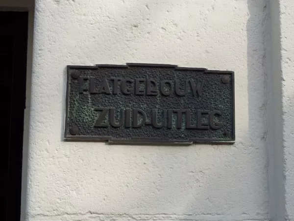 Afbeelding uit: maart 2012. Naast een van de portieken is deze plaquette aangebracht, met de tekst "Flatgebouw Zuid-uitleg".