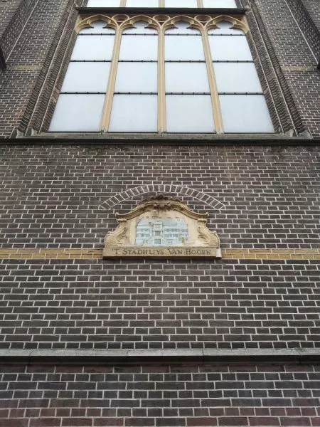 Afbeelding uit: april 2012. Gevelsteen met een fraaie rococo-lijst. De tekst 't Stadhuys van Hoorn verwijst naar de naam van de schuilkerk die hier stond voordat de huidige kerk werd gebouwd.