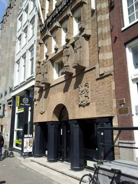 Afbeelding uit: mei 2012. De sculpturen zijn flink aangetast. Ze zijn gemaakt door Hildo Krop en stellen voor (v.l.n.r.) welvaart, arbeid, zorg en rust.

Links boven de ingang het wapen van Amsterdam; rechts het wapen van Friesland.