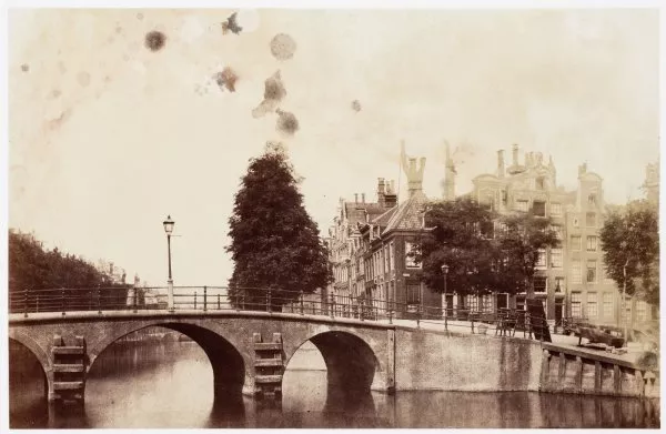 Afbeelding uit: mei 1857. De Britse fotograaf Turner maakte in 1857 deze foto van de voorganger van de huidige brug. Het is een van de oudste foto's van Amsterdam.