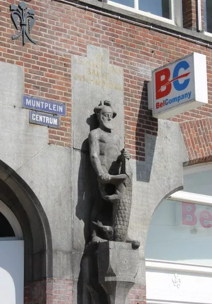 Afbeelding uit: mei 2012. Beeldhouwwerk op een console rechts van de hoek Kalverstraat. De sculptuur toont de Verzekering die een krokodilachtig monster uitschakelt. De tekst luidt "Ick en maek u den brant onschadelijk".