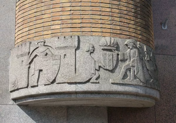 Afbeelding uit: mei 2012. Dit reliëf in graniet aan het Rokin toont keizer Maximiliaan die Amsterdam het recht geeft om de keizerskroon boven het wapen van de stad te voeren. Het is gemaakt door Mari Andriessen.