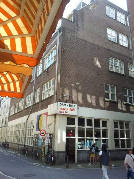 Afbeelding uit: juli 2012. Hoek Hermietenstraat/Nes. De onderpui is inmiddels vervangen door een nieuwe, met grote winkelramen.