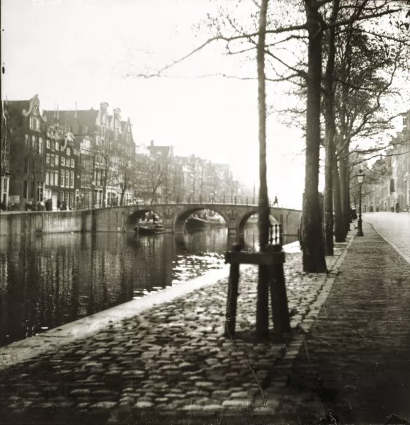 Afbeelding uit: Vóór 1894. De foto is gemaakt voordat de Raadhuisstraat werd aangelegd. Al in 1894 werd de brug lager en breder gemaakt.
