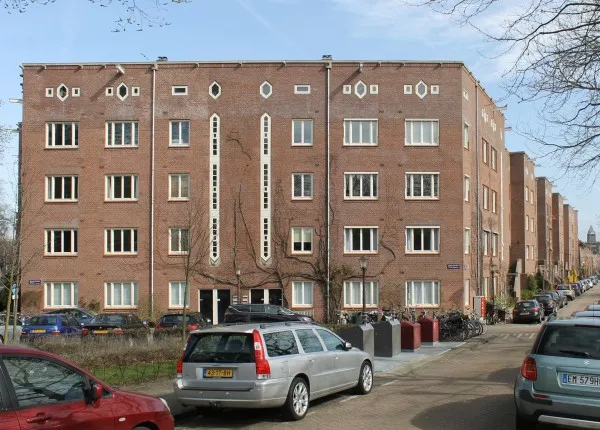 Afbeelding uit: maart 2017. De geheel vlakke gevelwand op de hoek met de Coenenstraat. Achter de verticale ramen bevindt zich het trappenhuis. Rechts de Reijnier Vinkeleskade.