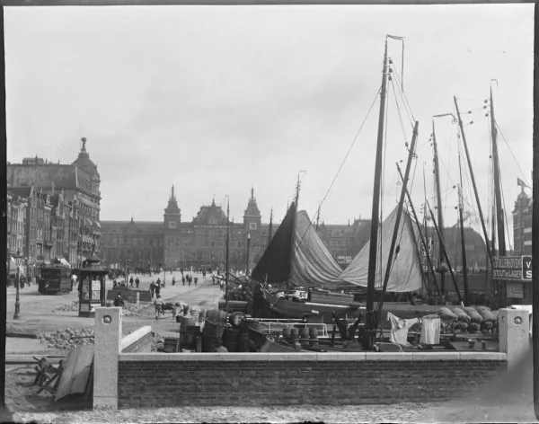 Afbeelding uit: september 1903. De bouw van het station betekende het einde van het Damrak als haven. Een deel van het water werd gedempt. De straat werd nu de entree tot de stad voor treinreizigers. En een toplocatie voor hotels, zoals het Victoria-hotel op de hoek.