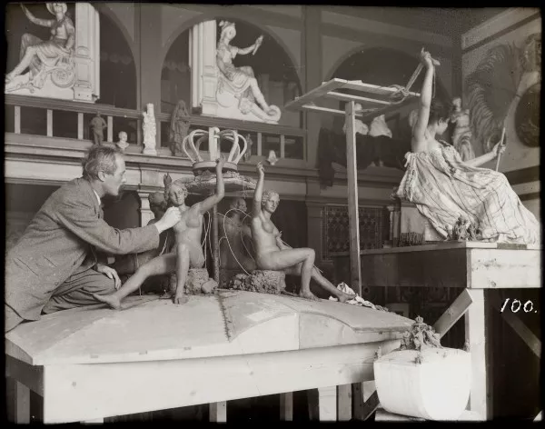 Afbeelding uit: 1898. Van den Bossche aan het werk met het beeldhouwwerk van de Gouden Koets. Foto uit het archief van de firma Spijker.