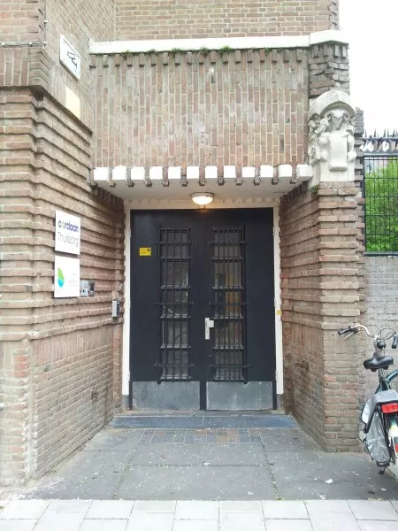 Afbeelding uit: mei 2013. De ingang rechts is versierd met beeldhouwwerk van Hildo Krop, voorstellende een schrijvende ram met een penneveer.