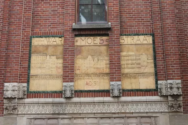 Afbeelding uit: juni 2013. Dit en nog twee terracotta reliëfs aan de gevel in de Warmoesstraat tonen de huizen die voor de bouw van de beurs werden gesloopt.