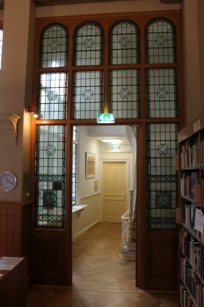 Afbeelding uit: juli 2013. Glas-in-loodpartij in de bibliotheek. In de onderste ramen zijn de letters F en S verwerkt, Fides en Scientia.