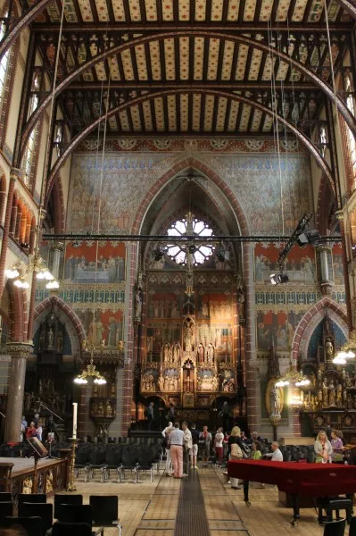 Afbeelding uit: juli 2013. Het schip gezien naar het altaar. Plat plafond, gedragen door ijzeren balken en bogen. Fresco's aan weerszijden van het altaar in de stijl van de 15e-eeuwse Dominicaner schilder-monnik Fra Angelico.